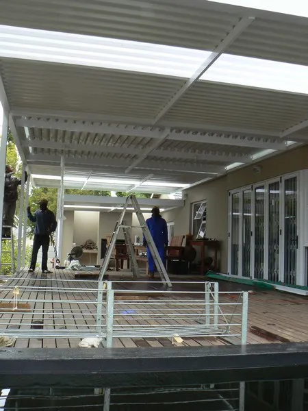 AL Patio Solutions installers fitting a white combination roof with louvre and polycarbonate panels over a long timber deck