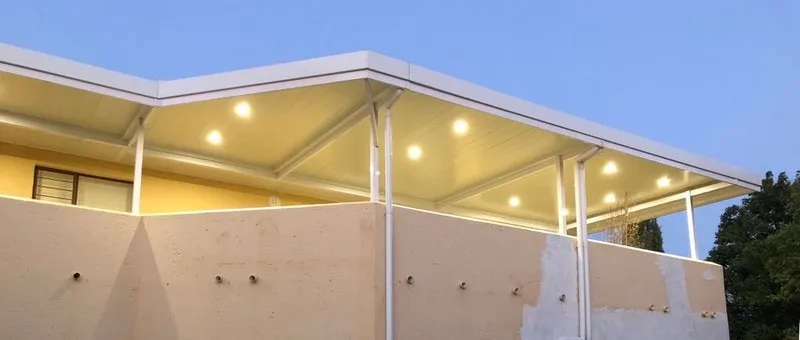 Downlighters glowing in an awning ceiling at dusk