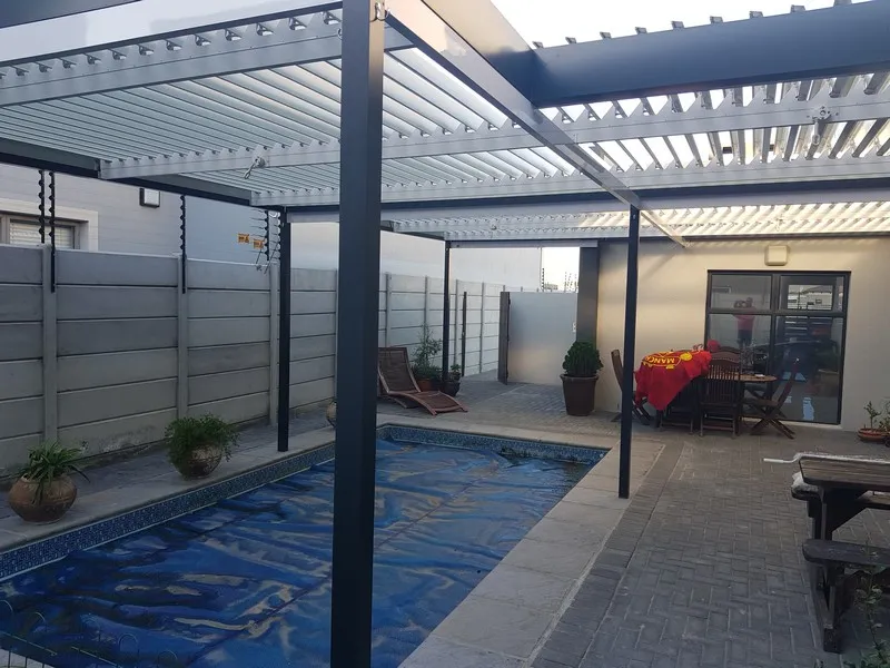 Louvre panels spanning a pool courtyard at a coastal home