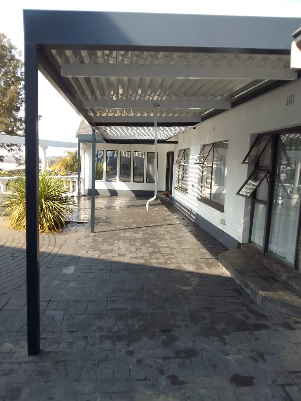 Second angle of the long charcoal veranda awning on a white Northcliff home